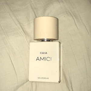 Parfym CAIA AMICI - Säljer en elegant parfymflaska från CAIA med namnet AMICI. Flaskan är stilrent designad i en ljus beige färg med en matchande kork. Perfekt för den som söker en sofistikerad doft.❤️flaskan är precis nästan full bara använt nån enstaka sprut.