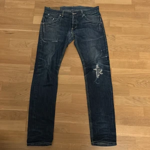 Dondup jeans  - Säljer ett par blå jeans med coola slitningar och klassisk femficksdesign. Jeansen har en normal passform och är tillverkade i 100% bomull för en bekväm känsla. Perfekta för en avslappnad stil. Passform Sam vilket är slim (proffesionellt fixade i skrevet skriv för bilder)