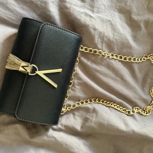 Valentino väska  - En svart helt ny valentino väska med guld kjedja. Den har använts 1 gång och säljer för den inte passade mig riktigt og pris är 885kr men säljer för 700kr eftersom den är såpass ny🩷💕priset kan diskuteras 