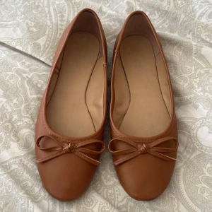 Bruna ballerinaskor med rosett från Anna field - Snygga bruna ballerinaskor i syntetmaterial med en söt rosett på tån. Perfekta för en stilren look. Säljer då jag insåg att dom är en st mindre än vad jag har🤭😪Skorna är sparsamt använda , de två sista bilderna visar väldigt litet slitage som man inte alls tänker på!! Men ville nämna det ändå tänker jag🍓👏🏼☀️