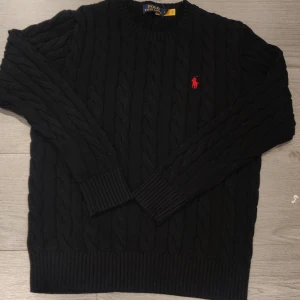 Svart Ralph Lauren tröja  - Säljer en klassisk svart stickad tröja från Ralph Lauren. Tröjan är replika men ser exakt ut som äkta. Tröjan är helt ny med tag. Storlek M men den passar mer de som bär storlek S. Det här är det lägsta priset jag kan erbjuda.