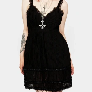 Svart klänning från Disturbia - Snygg svart klänning från Disturbia med spetsdetaljer och v-ringning. Klänningen har smala axelband och en plisserad design som ger en elegant look. Perfekt för en kväll ute eller en speciell tillställning.