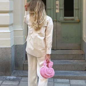 Rosa stickad handväska - Säljer en söt rosa stickad handväska med ett unikt flätat mönster. I nyskick 