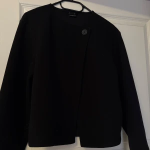 Svart kappa från Gina tricot  - En snygg svart kappa från Gina tricot som är helt perfekt nu till våren. jag köpte den för några månader sedan. Den är aldrig använd och är därför som ny. 