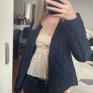 Mörkblå quiltad jacka från Uniqlo - Säljer min  mörkblåa quiltade jacka från Uniqlo. Jackan har en rund halsringning och knäppning framtill. Använd en vår men har inga större defekter. Den är i bra skick utan fläckar. Lite skrynklig men annars bra. Skriv om du har fler frågor🩷