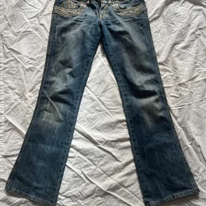 Blå jeans från Take Two - Snygga blå jeans från Take Two med bootcut-stil. De har en klassisk femficksdesign och slitna detaljer på bakfickorna. midjemått:37 innerbenslängd:80