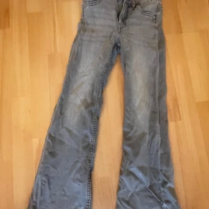 Grå jeansbyxor - Säljer ett par grå jeansbyxor med bootcut-stil. Byxorna har en klassisk femficksdesign och är perfekta för en avslappnad look. De är tillverkade i ett slitstarkt material och har en bekväm passform.