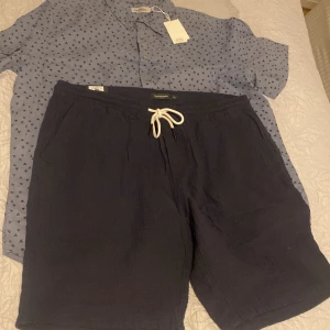 Svarta shorts från Dressmann - Snygga svarta shorts från Dressmann med bekväm snörning i midjan. Perfekta för en avslappnad stil under varma dagar.