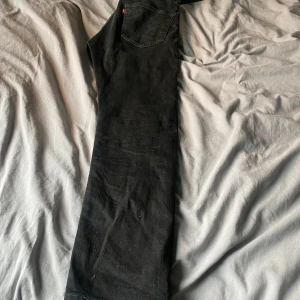 Svarta jeans från Levi's | Levis 502 - Snygga svarta jeans från Levi's med klassisk femficksdesign och dragkedja. Perfekta för en stilren look. Märkesetikett på baksidan och röd Levi's-flik vid bakfickan. W30L30