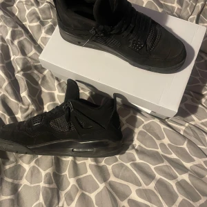Jordan 4 black cats - Säljer ett par svarta sneakers med snörning och rund tå. Skorna har en stilren design med detaljer i syntetmaterial och mesh. Perfekta för en casual look. De e använd under vinter och har små små skador på sidorna och vid hällen i skorn. ‼️‼️Fråga gärna om fler bilder om du undrar ‼️‼️