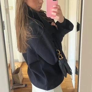 Marinblå kappa  - Säljer en stilren marinblå kappa med knappar framtill. Jackan har en klassisk krage och en något lös passform, perfekt för vår. En tidlös design som passar till många olika outfits. Den är i nytt skick i storlek M men skulle säga att den sitter som en S.