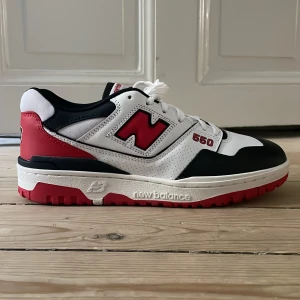 New Balance 550 sneakers i vitt, svart och rött - Snygga New Balance 550 sneakers i en fräsch färgkombination av vitt, svart och rött. Skorna har en rund tå och snörning för en bekväm passform. Perfekta för en sportig look. Jag har kvar newbalance boxen till skorna, sprillans nya ”straight out of the box”