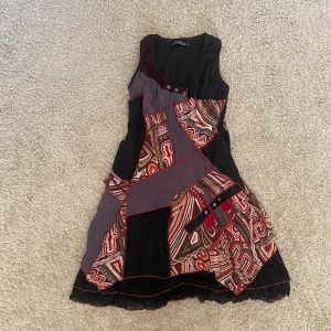Unik patchwork klänning - Säljer ett av mina absolut favoritplagg eftersom jag inte har tillfälle att bära det😭Klänningen är sydd i patchwork med röda band-detaljer, passar perfekt med ett par jeans under eller ett par boots💗