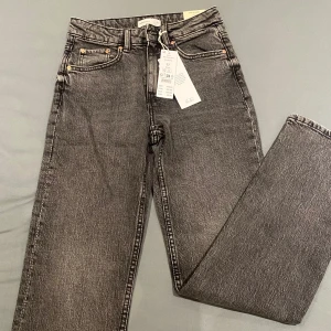 Washed grey jeans från gina tricot  - Snygga svarta jeans från Gina Tricot med en klassisk femficksdesign. De har en hög midja och raka ben, vilket ger en tidlös look. Perfekta för att matcha med olika toppar och skor.