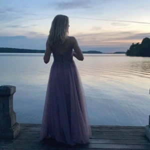 Ljuslila balklänning  - Elegant ljuslila långklänning med spetsdetaljer och smala axelband. Klänningen har en v-ringad design och en öppen rygg som ger en sofistikerad look. Har bara använt den en gång så den är som ny och är perfekt till balen!💕💕 Nypris 1600kr. 