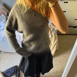 Grå kashmirtröja från Soft Goat - Säljer en stilren grå kashmirtröja från Soft Goat. Tröjan har en unik oneshoulder-design och är ribbstickad för extra komfort. Passar bra till både jeans och kjol.