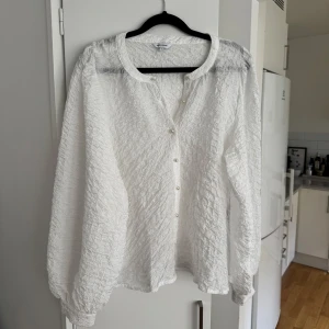 Vit blus med knappar - Super fin blus med lite balongärmar och fina pärlknappar. Använd 1 gång, köpt på bubbleroom. Storlek L men skulle säga att det är mellan M/L