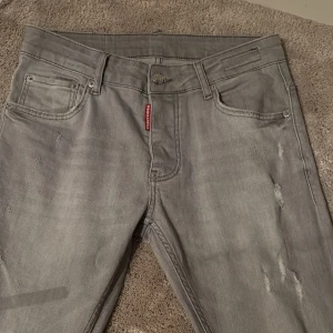 Grå jeans från Dsquared2 - Snygga grå jeans från Dsquared2 med en cool slitningseffekt. De har en klassisk femficksdesign och en knappgylf. Perfekta för en stilren look med en touch av edge.