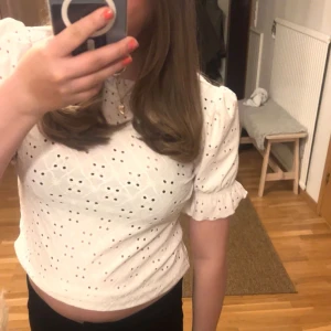 Vit blus med broderade detaljer - Säljer en söt vit blus med broderade hålmönster och puffiga kortärmar. Perfekt för en somrig look. Blusen har en rund hals och en lätt croppad passform.🥹💖🥂🙏🏼