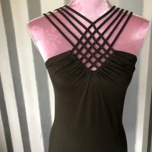 Brun linne med korsade axelband - Snygg brun topp med unika korsade axelband och rynkad detalj framtill. Perfekt för en stilren look.