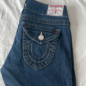 Snygga jeans från True Religion  - Snygga blå jeans från True Religion med klassisk femficksdesign och dekorativa sömmar. Byxorna är i väldigt bra skick och använda ett mycket fåtal gånger. De är lågmidjade och lite mer raka i modellen men fortfarande riktigt snygga.                                  Mått: midjemått är 37,5 cm, innerbenslängd är 74, hela byxan är 94 cm och midjehöjden är 18,5 cm. Ett riktigt måste i garderoben och funkar till både fest och vardag.🐙🤗❤️