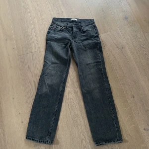 Svarta/grå jeans från Gina Tricot  - Snygga svarta/gråa jeans från Gina Tricot med en klassisk straight passform. Perfekta för en stilren look. De har en traditionell femficksdesign och knappgylf.