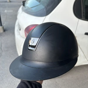 Svart ridhjälm från Samshield -  Säljer nu min ridhjälm. Det är en SAMSHIELD MISS SHIELD SHADOWMATT. Storlek M i skalet och 56 i linner. Den är använd men i fint skick. Aldrig tappat eller avramlad i. Egna bilder kan fixas vid intresse.