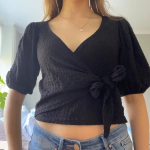 Svart omlottopp med knyt - Säljer en svart omlottopp med knytning i midjan💓