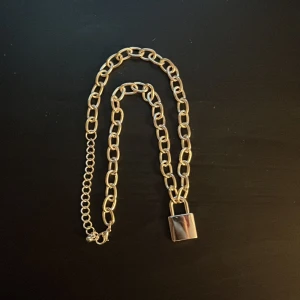 silverfärgat halsband med hänglås - Snyggt silverfärgat halsband med ett trendigt hänglås som detalj. Kedjan har en robust design och ger en cool touch till din outfit. Perfekt för att lyfta vilken look som helst. Köptes från H&M men har aldrig använts