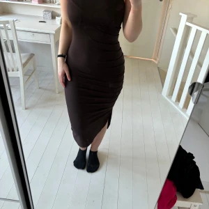 Brun klänning med slits - Brun klänning med smala axelband och en  slits på sidan. 