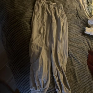 Gråa mjukisbyxor med resår - Säljer ett par gråa mjukisbyxor med resår i midjan och vid bensluten. Byxorna har en avslappnad passform och är perfekta för chill dagar. Tillverkade i mjukt material för extra komfort.