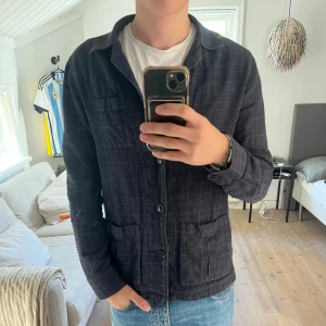 Rutig overshirt från John Henric - Snygg mörkblå rutig overshirt från John Henric. Jackan har klassisk krage, tre framfickor och stängs med knappar. Perfekt lager-på-lager-plagg med avslappnad passform och mjukt tyg i bomull.