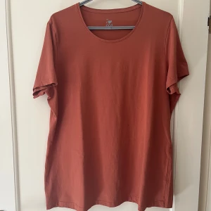 Rostbrun t-shirt ICA I Love Eco strl XXL - Snygg rostbrun t-shirt från ICA I Love Eco i storlek XXL. Tillverkad av mjuk ekologisk bomull med lite stretch för extra komfort. Klassisk rund hals och korta ärmar. 