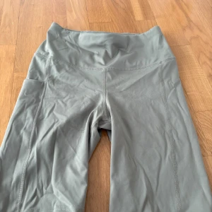 Grå höga leggings från SXS - Snygga olivgröna cykelschorts från SXS i storlek S. De är högmidjade med bred linning, har praktiska sidofickor och scrunch-detalj bak. Tillverkade i stretchigt syntetmaterial som passar perfekt för träning eller chill. Lite stretch vid rumpan 