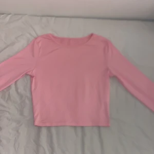 Rosa långärmad topp - En enkel och stilren rosa långärmad topp med rund halsringning. Perfekt att matcha med jeans eller kjol för en avslappnad look. Mjuk och skön känsla mot huden.