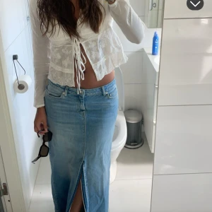 Vit blus med snörning från Zara - Säljer en vit blus från Zara med långa ärmar och snygg snörning framtill. Blusen har spetsdetaljer och broderade blommor. Storlek M. Använd typ 1 gång 