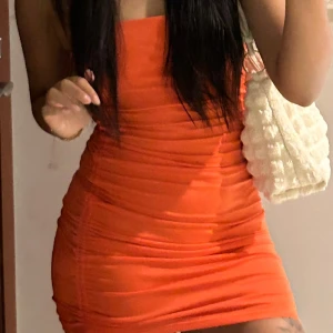 Orange ruched klänning från Divided - Säljer en snygg orange kortklänning från Divided med smala axelband och ruched detaljer längs sidan. Klänningen har en tight passform. I superbra skick 😊