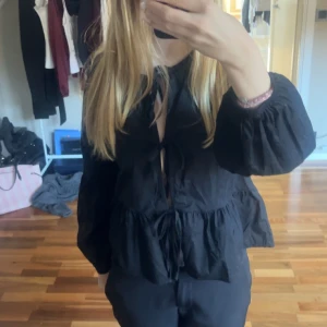 Svart blus med knyt och volang - Svart blus från Missäy med rosetter fram och puffiga ärmar. I storlek XS/S! 🖤Har även en i vit så skriv om ni är intresserade av den.