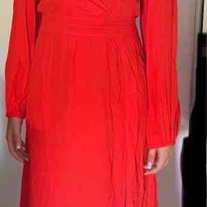 Röd klånning med långa ärmar med prislapp fr.BikBok - Snygg röd klänning med långa ärmar och markerad midja. Klänningen har v-ringning och en lätt slits framtill. Materialet är mjukt och faller fint, perfekt för dig som vill sticka ut med en färgstark look. Etikett med prislapp är kvar,599:- står på. Inköpt på Bik Bok. 