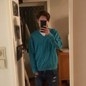 Ljusblå V-neck från tommy hilfiger - Säljer denna relativt oanvända pullovern då den är för stor för mig. Den är 100% bomull och i ganska bra skick. Inte för varm men perfekt för hösten. Hör av er vid frågor🙌