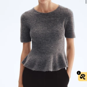 Grå ribbad topp med volang - Säljer en grå ribbad topp med korta ärmar och rund hals. Toppen har en snygg volangkant nedtill som ger en feminin siluett. Materialet är stickat och känns mjukt mot huden. Perfekt för dig som gillar stilrena och trendiga plagg. Använd en gång, köpt för 220❤️