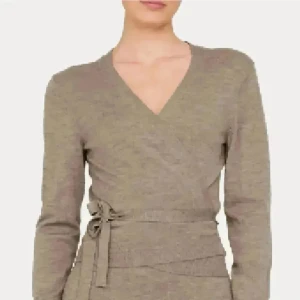 Beige omlottkofta med knytband 100% Merinoull - Säljer en beige omlottkofta med v-ringning och knytband i midjan. Koftan har lång ärm och är tillverkad i ett mjukt stickat material 100% Merinoull som känns skönt mot huden. Perfekt för lager-på-lager och enkel att styla till olika outfits. 1 gång använd och tvättat. Köpt för 799 på Cubus