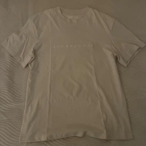 Beige t-shirt från Jack & Jones XS - Snygg beige t-shirt från Jack & Jones Originals i storlek XS. T-shirten har rund halsringning, korta ärmar och diskret logga framtill. Tillverkad i mjuk bomull för en skön känsla och enkel stil.