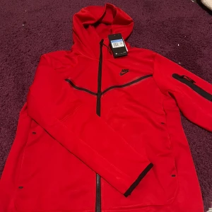 Röd Nike tech fleece kofta - Helt ny och oanvänd, storleken på den är M men jag har storlek S och den passar mig. Kan mötas upp i norrköping.