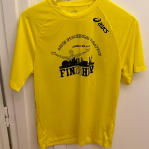 Gul Asics Stockholm Marathon Finisher t-shirt - Gul t-shirt från Asics med tryck 'Stockholm Marathon Finisher' på bröstet. Modellen är kortärmad och tillverkad i 100% polyester, perfekt för löpning eller träning. Asics-logga på axeln och ryggen. Snygg sportig vibe och skön passform. Storlek M.