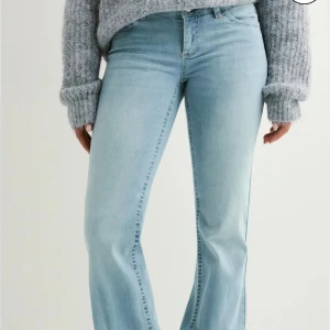 Ljusblå bootcut jeans med brodyr - Snygga ljusblå jeans med bootcut passform och broderade detaljer i rosa på bakfickorna. Jeansen har klassisk femficksdesign och är tillverkade i mjukt denimtyg som sitter skönt. Perfekta för dig som gillar en retroinspirerad look.