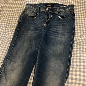 Blå Replay jeans, midwaist, storlek 28/32 - Säljer ett par snygga blå jeans från Replay i modellen M914, midwaist med klassisk femficksdesign och ljusa slitningar. Jeansen har raka ben och coola detaljer på bakfickorna. Perfekta för dig som gillar en tidlös och avslappnad look.