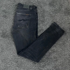 Svarta Nudie Jeans | Slim Fit - Säljer ett par riktigt feta svarta slim jeans från Nudie Jeans med en go diskret slitning. Slim fit. Perfekt för en stilren look. Tveka inte på att höra av dig vid minsta tanke eller fundering! 😁