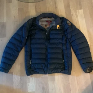 Mörkblå dunjacka Parajumpers Y-L - Säljer en mörkblå dunjacka från Parajumpers i storlek Y-L. Jackan är superlätt, har quiltad design, dragkedja framtill och två sidofickor. Klassisk Parajumpers-detalj vid kragen och patch på ärmen. Perfekt för kalla dagar och riktigt snygg passform. Sitter som storlek S 