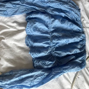 Blå offshoulder blus från Bik Bok - Säljer en ljusblå blus från Bik Bok i storlek XS. Blusen har offshoulder-modell, långa ärmar och broderade blommor över hela tyget. Volangdetaljer vid midjan och nederkanten ger en söt och feminin look. Perfekt för vår och sommar!